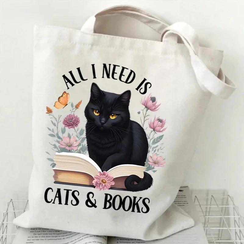 A white canvas tote bag featuring a black cat and butterfly design with the text Cats & Books printed on it.