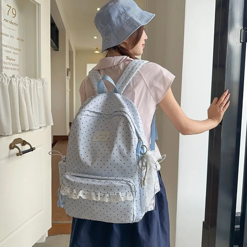 A woman wearing a light pink shirt and blue hat carries a light blue polka dot nylon travel backpack.