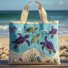 A light blue quilted canvas tote bag featuring various colorful sea turtles and coastal landscape designs.