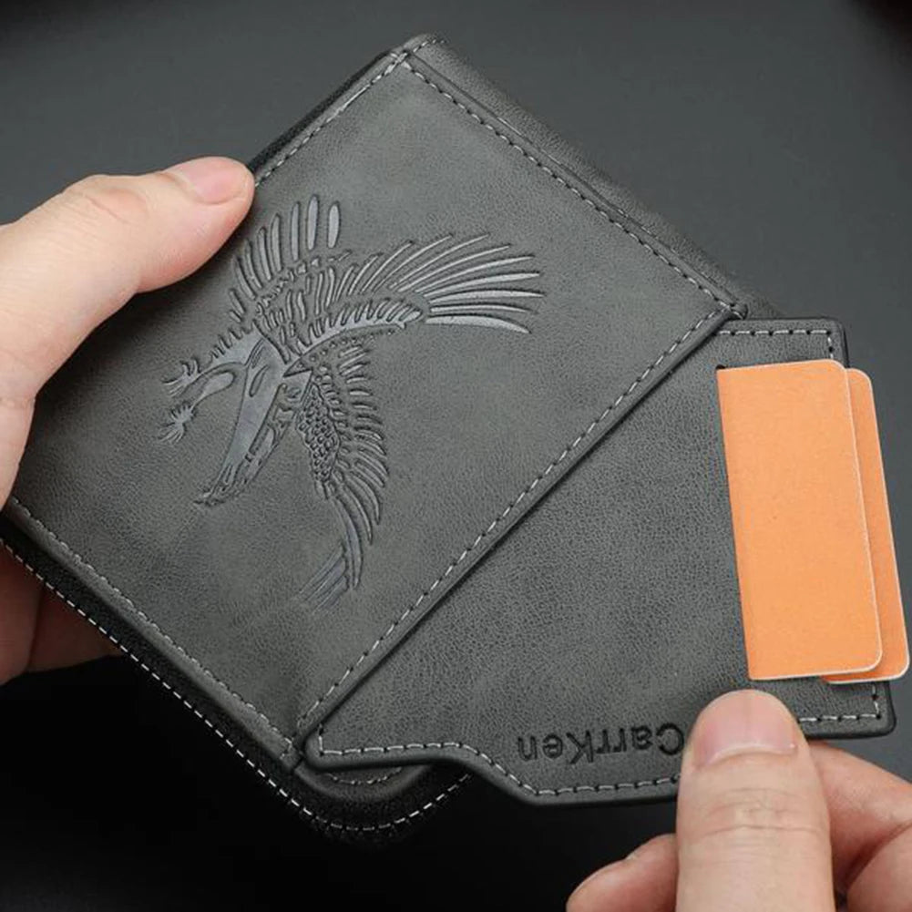 Cartera de cuero gastado gris oscuro con diseño de águila estilizada y una tarjeta naranja, sostenida por una mano.