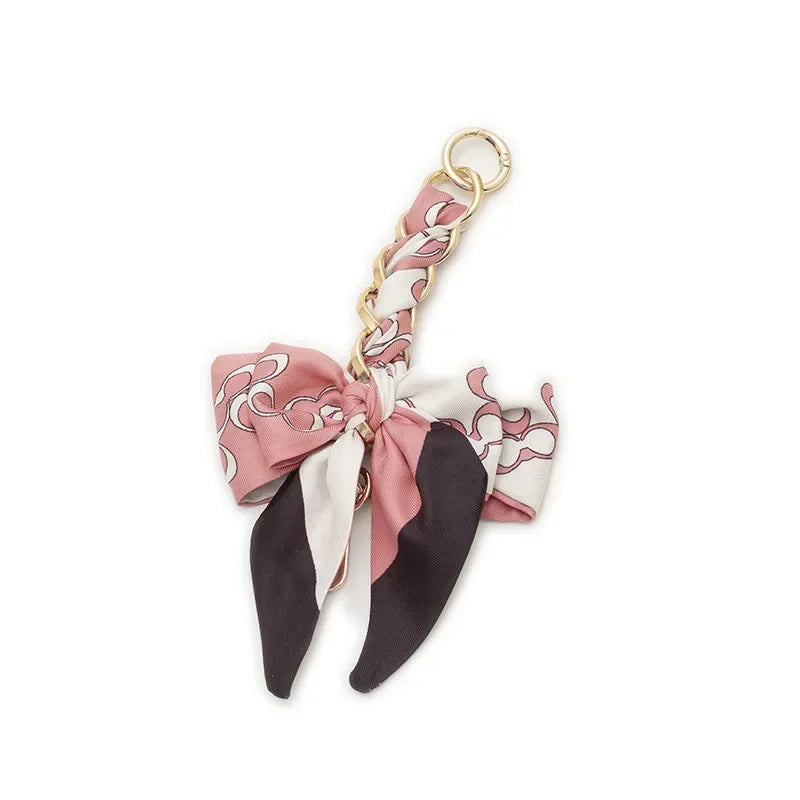 Pink and black patterned adjustable bag strap with a gold-tone metal clip.