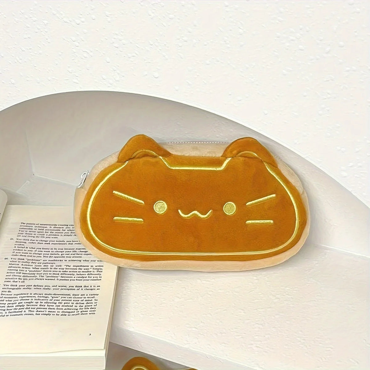 A golden caramel cat plush pencil pouch resting on a white surface.