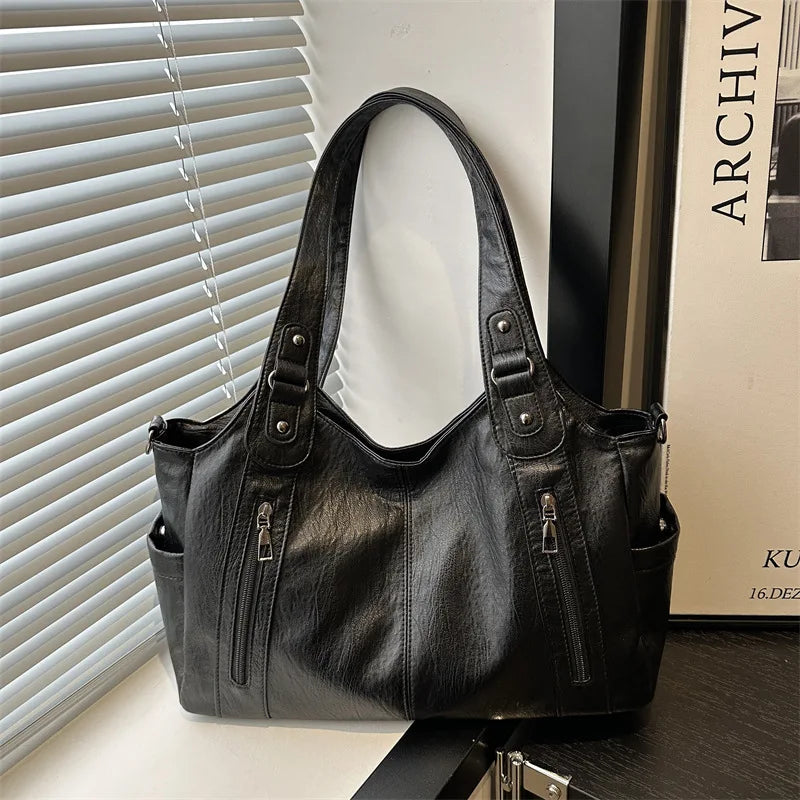 A black leather everyday large-capacity shoulder tote bag is shown against a white background.