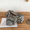A leopard print riveted Boston shoulder bag resting on a wooden surface next to a magazine.