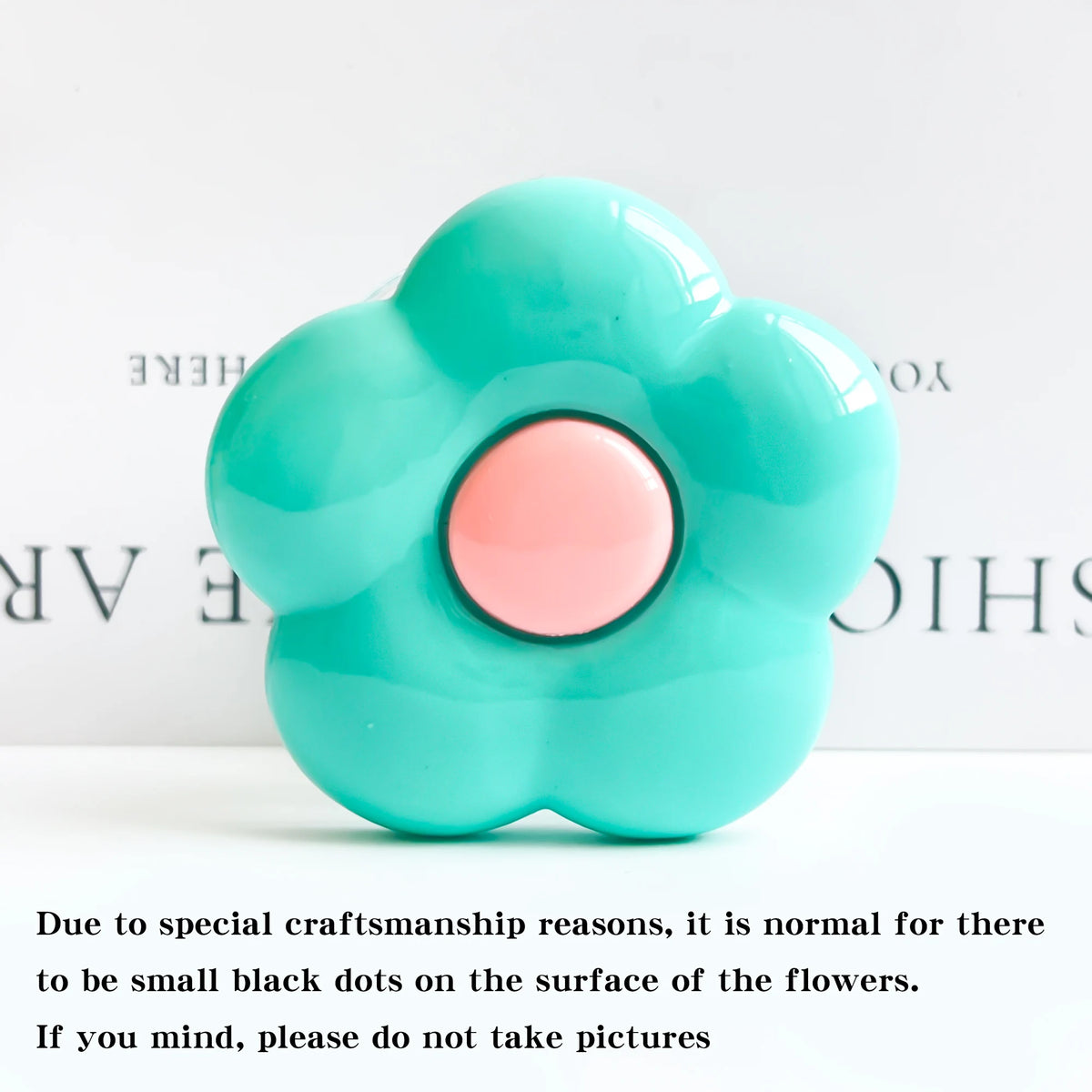 A light blue flower-shaped phone grip ring stand with small black dots on the surface.
