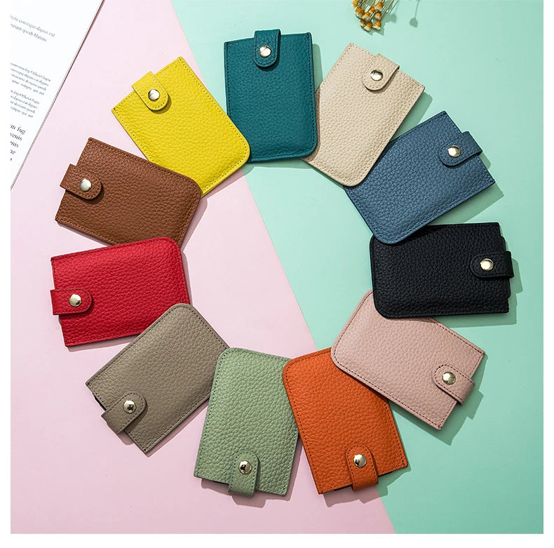A collection of genuine leather slim card holders in various shades of green, yellow, pink, and brown arranged on a light bac