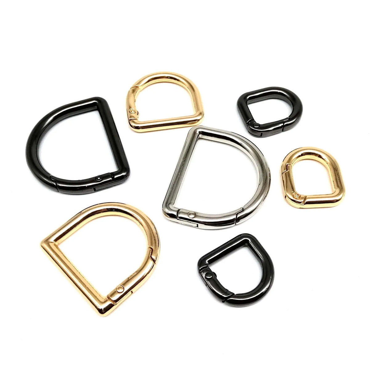 A collection of gold and black D-shape metal spring ring clasps for bags and keychains.