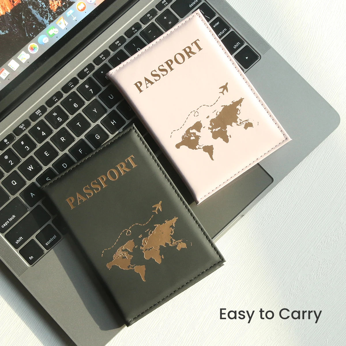 Zwei Leder-Reisepasshüllen mit goldenen Landkarten-Designs auf einem silbernen Laptop.