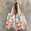 A light-colored reusable shopping bag with a patterned design featuring cute characters and colorful elements.