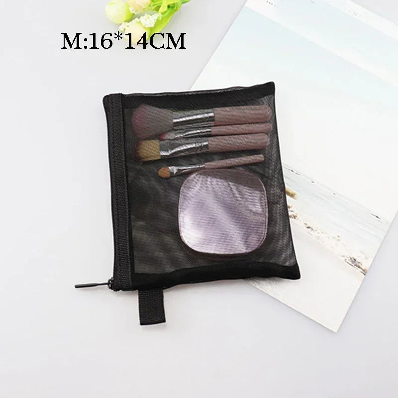 Black mesh cosmetic storage pouch containing several makeup brushes and a circular sponge