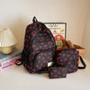 A black nylon travel backpack set featuring a cute red bow print design, displayed on a white surface.