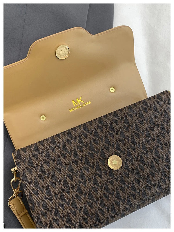 A tan Michael Kors letter square crossbody bag with gold hardware resting on a white surface.
