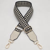 A black and white checkered braided nylon bag strap with beige leather accents and metal hooks.