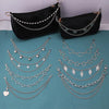 A display of multi-layer silver metal chain strap shoulder bags and charms on a teal background.