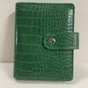 A green crocodile leather ring binder notebook.