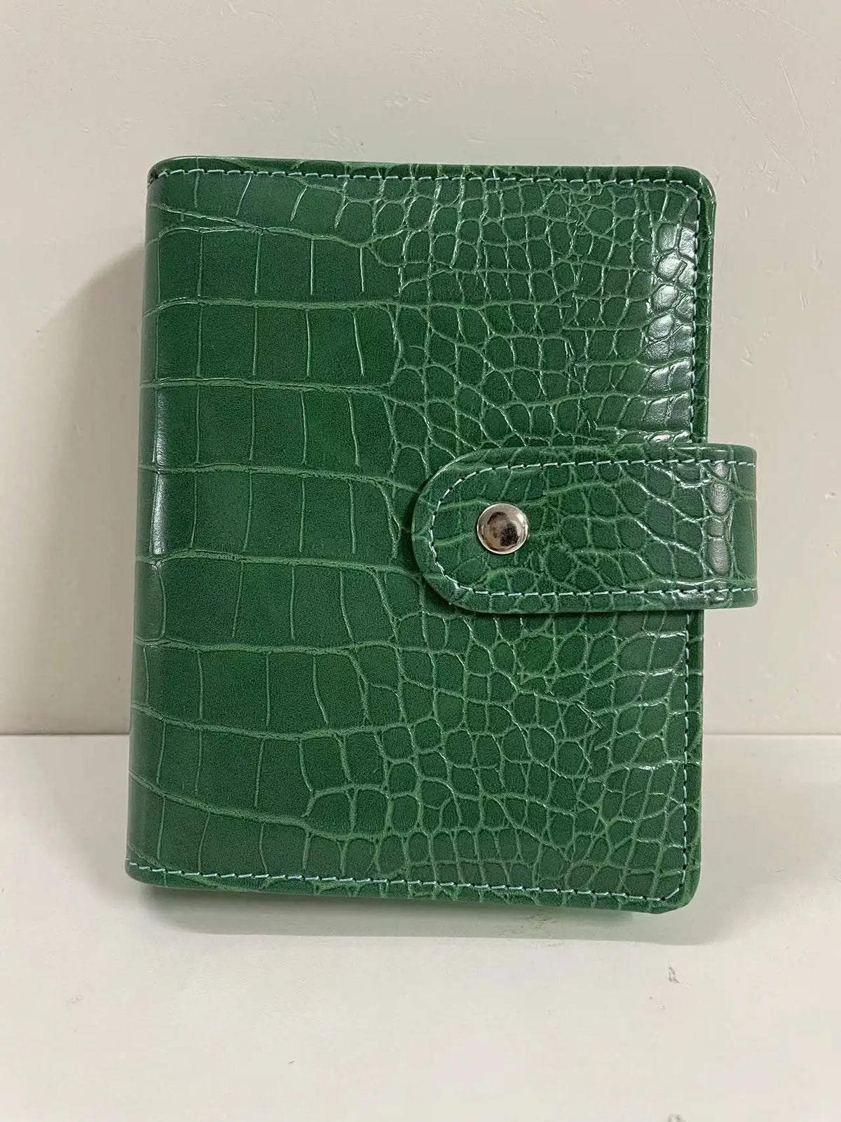 A green crocodile leather ring binder notebook.