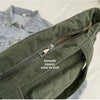 A close-up of a dark olive green corduroy shoulder bag with a zipper, shown against a light background.