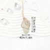 A hand sewn rhinestone beaded bag charm hanging from a gold thread against a white background.
