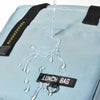 A light blue insulated lunch bag is shown with water dripping from the top, highlighting its waterproof features.