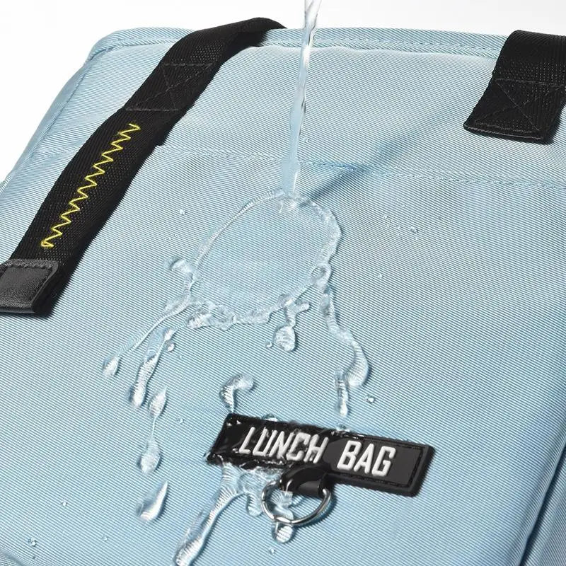 A light blue insulated lunch bag is shown with water dripping from the top, highlighting its waterproof features.