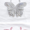 A close-up of a pink glitter rhinestone butterfly applique sticker with intricate detailing.