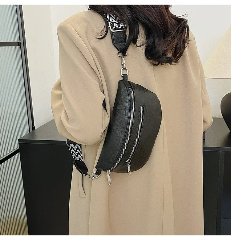 A woman holds a black PU leather multi-pocket crossbody bag with a patterned strap against a light beige coat.
