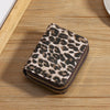 A brown and black leopard print double zipper wallet resting on a wooden surface.