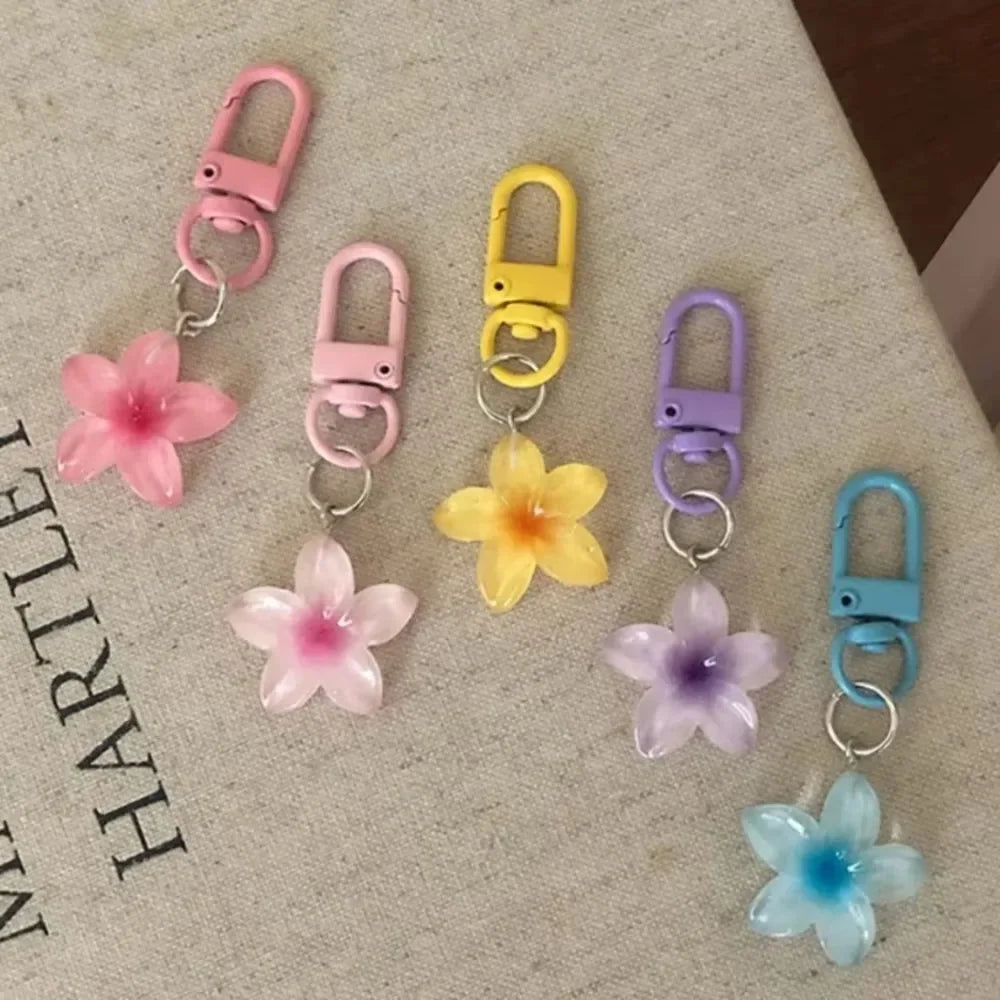 A collection of colorful resin flower keychains with metal clasps in pink, yellow, purple, and blue.