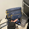 A hand holds a dark blue Rivet Waist Bag crossbody fanny pack against a black background.