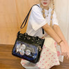 A young woman models a black Y2K punk goth crossbody bag with silver charms and iridescent embellishments.