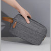 A hand is holding a gray fabric storage pouch with brown leather accents, showcasing its unique grid design.