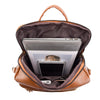 A brown leather backpack with a zipper opening showing a silver laptop and a black tablet inside.