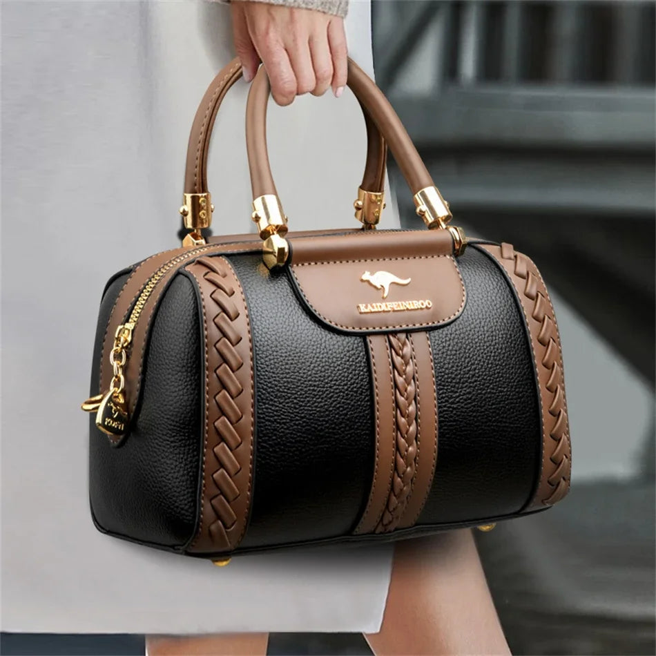 A brown leather shoulder crossbody bag with gold hardware and a quilted pattern is held by a person.