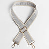 A beige and gray patterned adjustable crossbody bag strap with a gold-toned buckle.