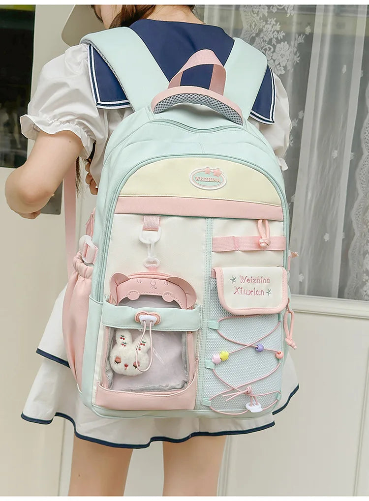 A light mint green and pink campus backpack worn by a woman.