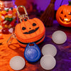An orange pumpkin shaped mini PU leather keychain accessory rests on a purple fabric surface with other small items.