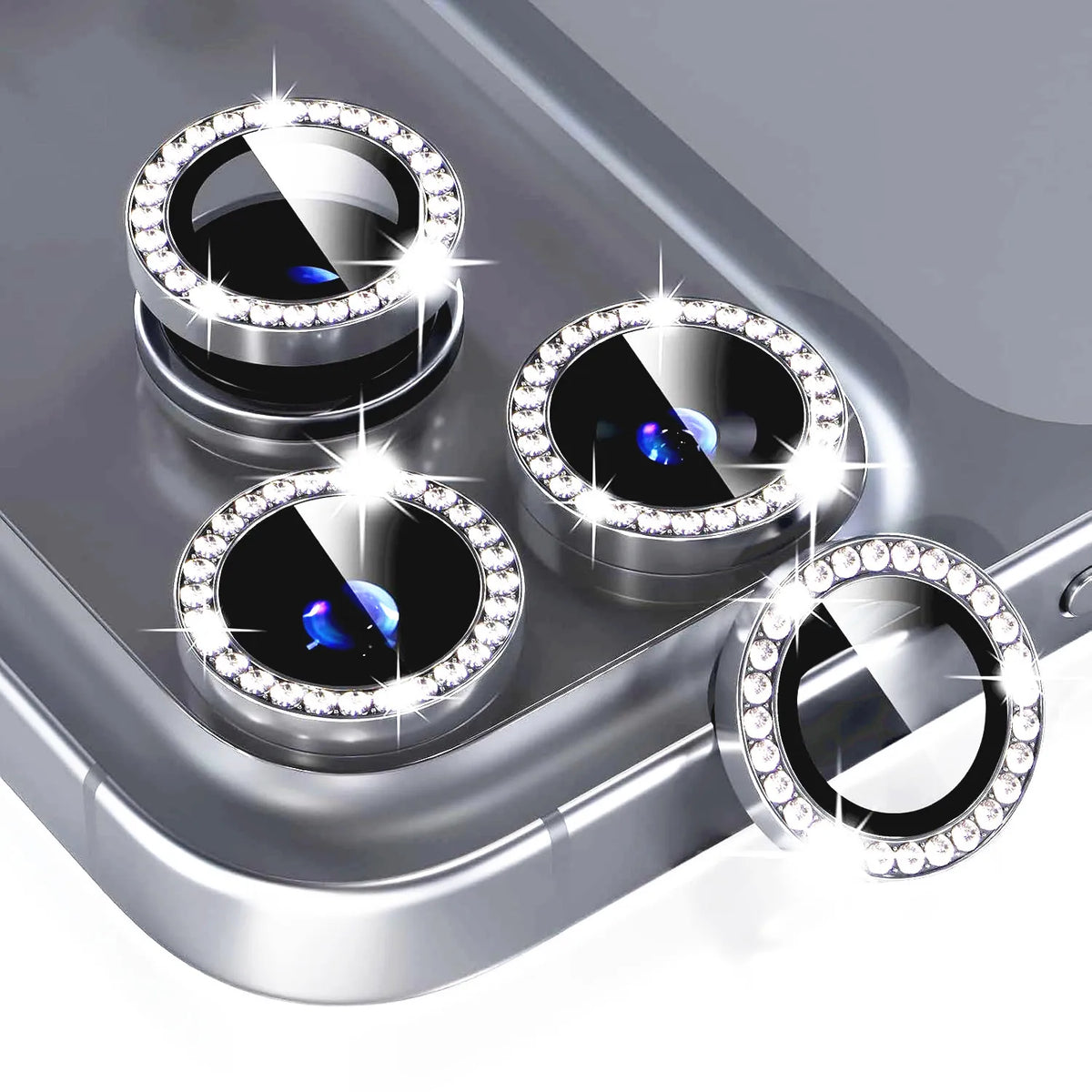 A close-up of a glitter diamond camera lens protector with a metal frame for an iPhone, showing multiple lenses.