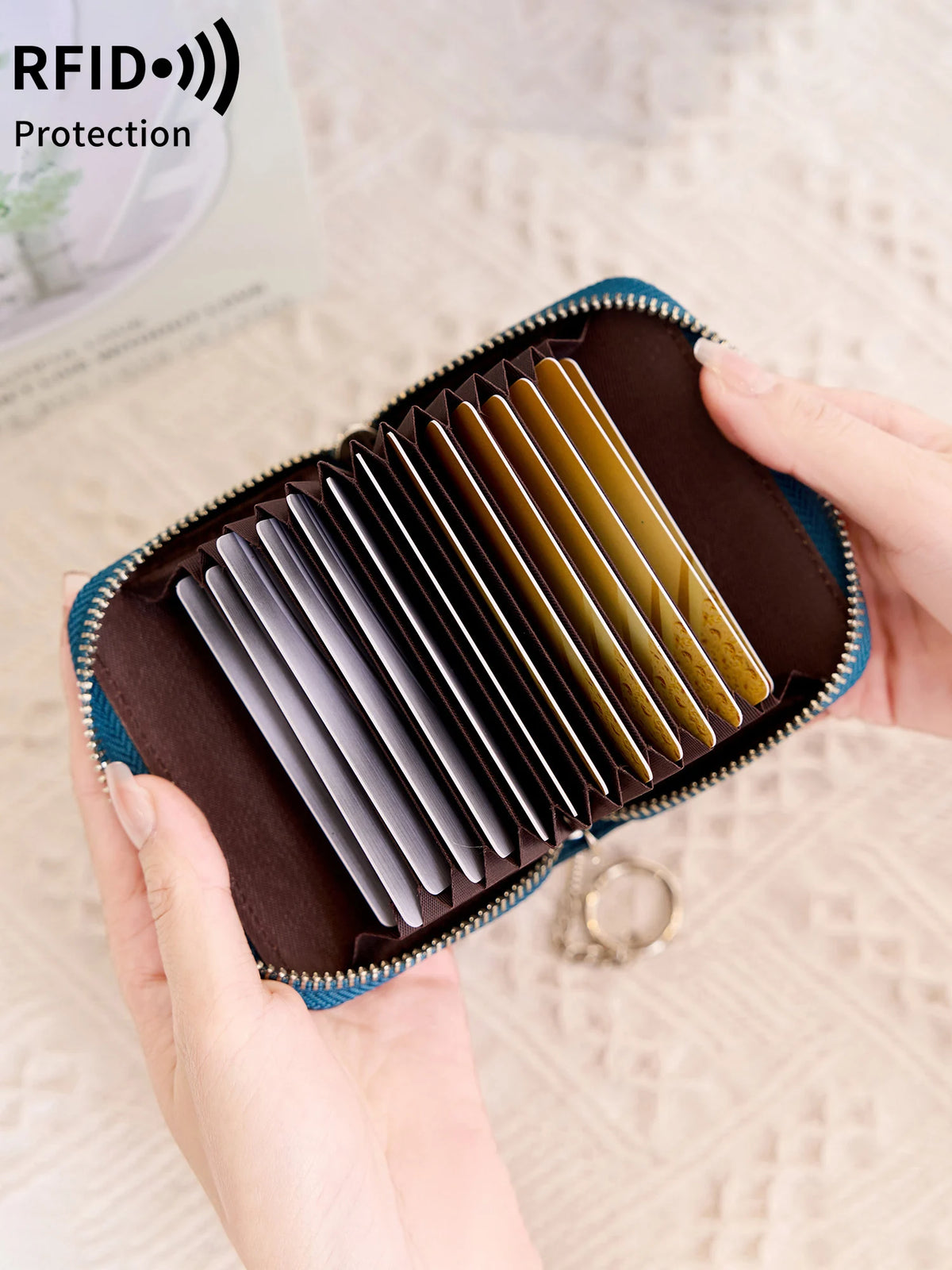 A hand holds an open brown accordion wallet with multiple protective layers for cards and IDs.
