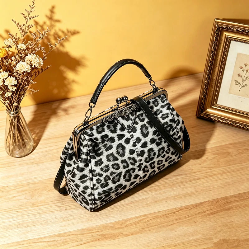 A black and white leopard print faux leather handbag with a top handle and crossbody strap resting on a wooden surface.