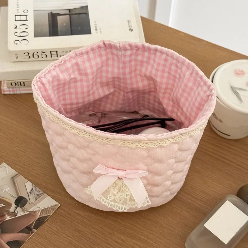 Cesta de almacenamiento de corazón acolchada de algodón rosa con lazo de encaje sobre una superficie de madera.