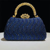 A royal blue crystal-embellished evening clutch bag with a gold crown clasp and chain strap.