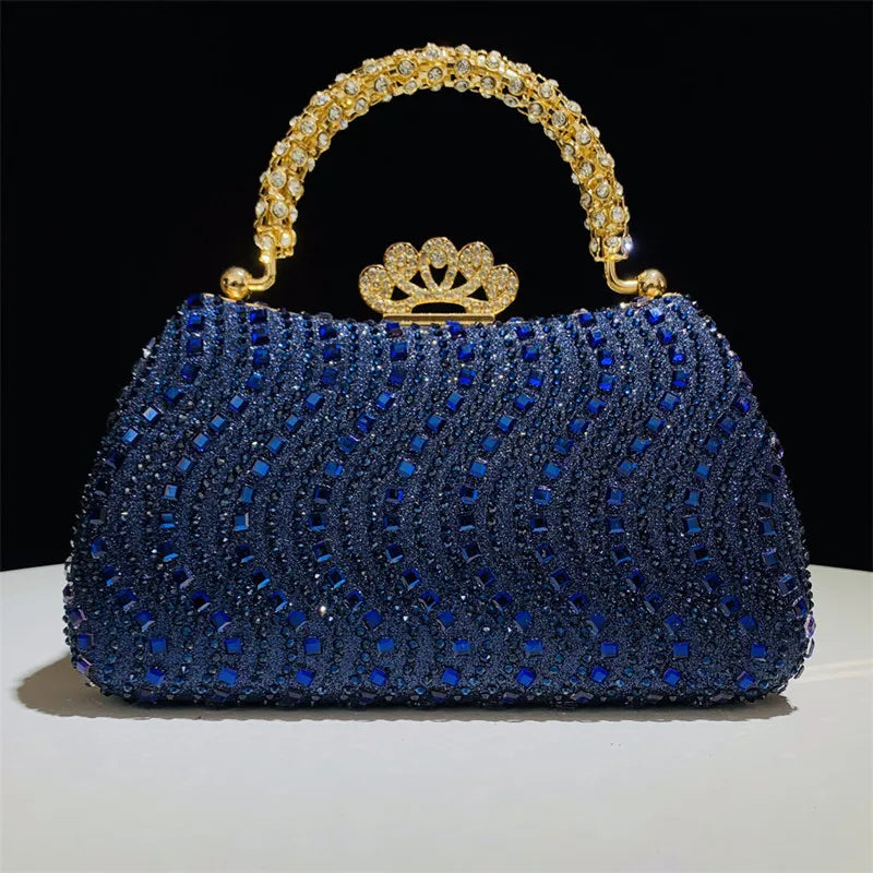 A royal blue crystal-embellished evening clutch bag with a gold crown clasp and chain strap.