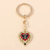 Gold heart-shaped keychain featuring a black butterfly pendant with red accents.