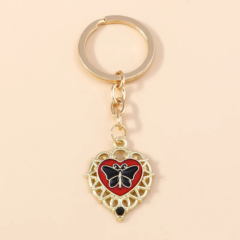 Gold heart-shaped keychain featuring a black butterfly pendant with red accents.