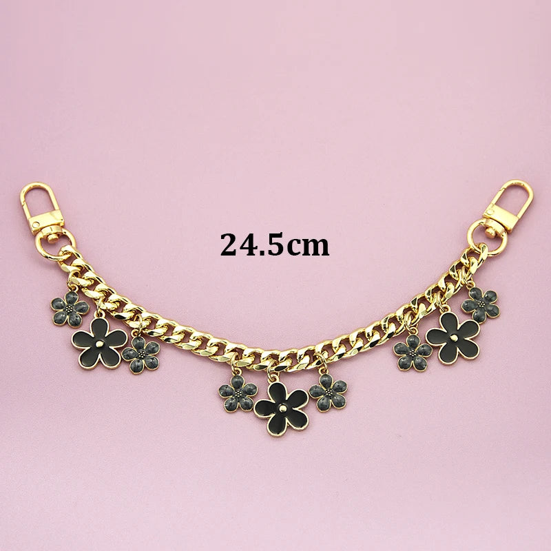 Gold chain necklace with black flower charms and a gold clasp, measuring 24.5cm.