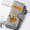 A gray zippered pouch featuring a tiger graphic on the cover, resting on a white background next to a laptop keyboard.