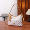 A beige crescent tote bag with a letter print and bow accent resting on a wooden table.