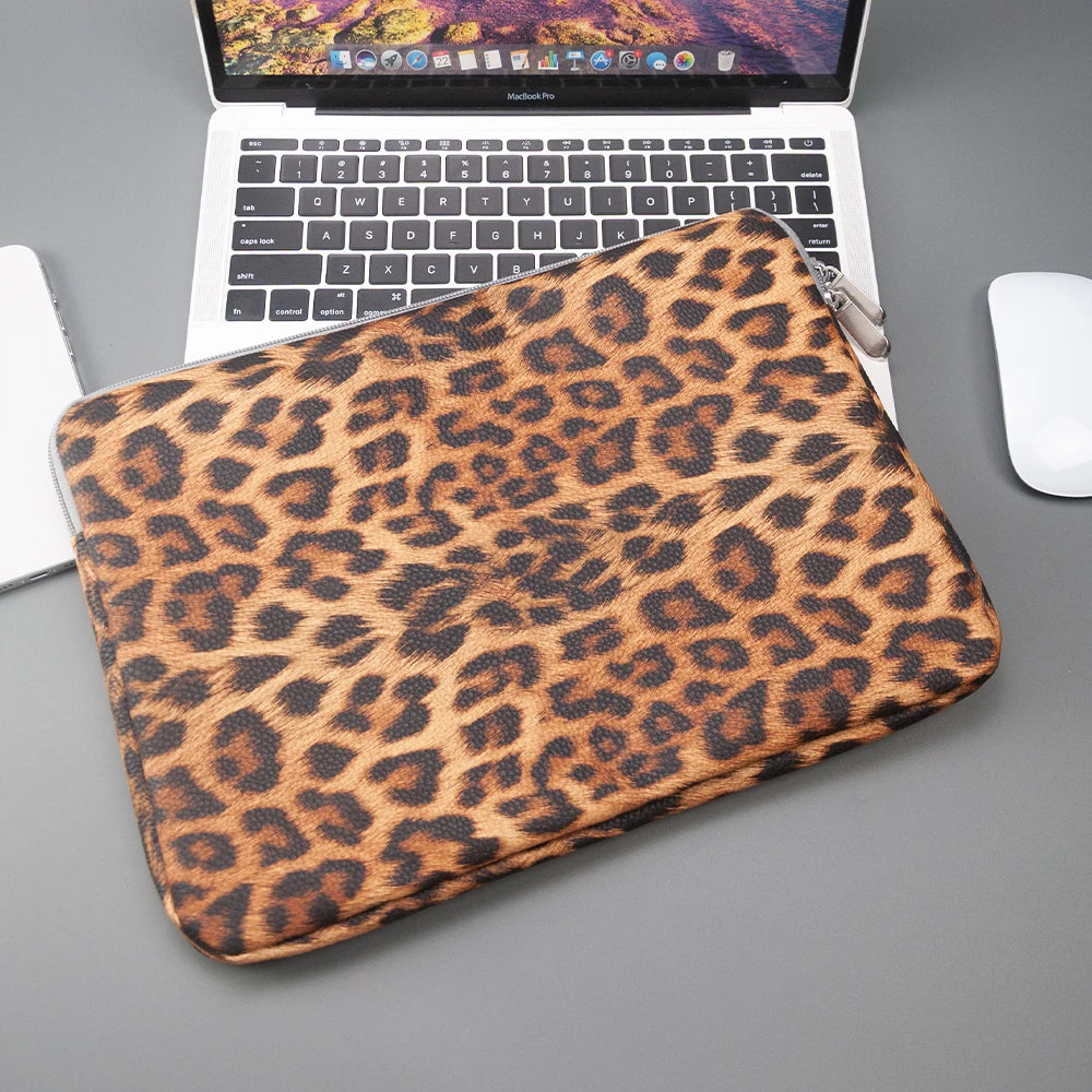 Braunes Leopardenmuster-Laptop-Cover auf grauem Untergrund neben einem geöffneten Laptop.