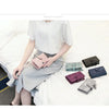 A woman wearing a light gray top and skirt is sitting on a white bed, holding several multi-slot card wallets.