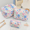 A pink and blue patchwork quilted makeup bag next to a butter-themed book.